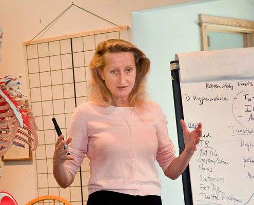 Donna teaching a class with a skeleton and easel nearby.