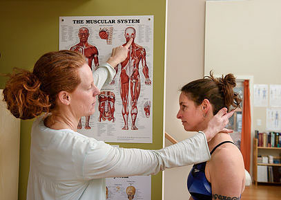 Stacy Earlywine instructing a client as she points to an anatomy illustration.